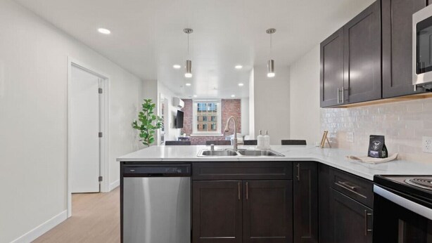 A modern kitchen with dark cabinetry, stainless steel appliances, and a central island.