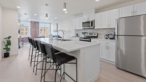 A modern kitchen with white cabinets, stainless steel appliances, and a central island with bar stools.