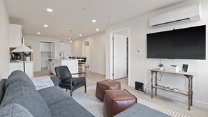 A modern living room with a grey sofa, a coffee table, and a TV mounted on the wall.