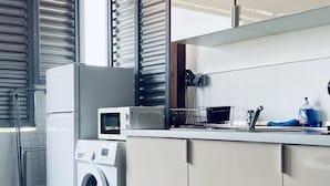 Een kleine keuken met een wasmachine, magnetron en spoelbak.