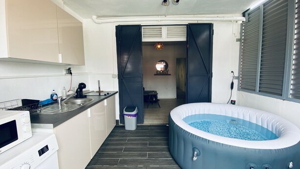 Een compacte keuken met een magnetron, spoelbak en een klein eethoekje. Een jacuzzi is in de voorgrond zichtbaar.
