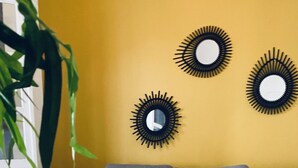 Een moderne woonkamer met een hoekbank, een klein rond tafeltje en decoratieve spiegelwand.