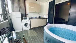 Een praktische keuken met een wasmachine, een magnetron en een klein eethoekje met een glazen tafel.