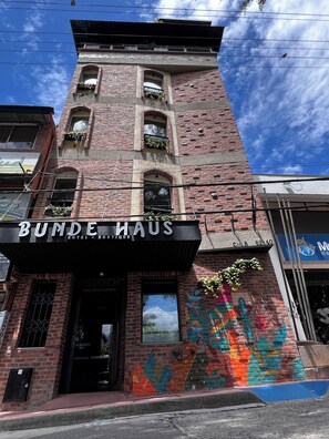 Een hotel genaamd 'BUNDE HAUS' met een bakstenen gevel, grote ramen en een kleurrijke muurschildering aan de zijkant.