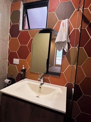 Een badkamer met een witte wastafel, een spiegel en een handdoek aan de muur.
