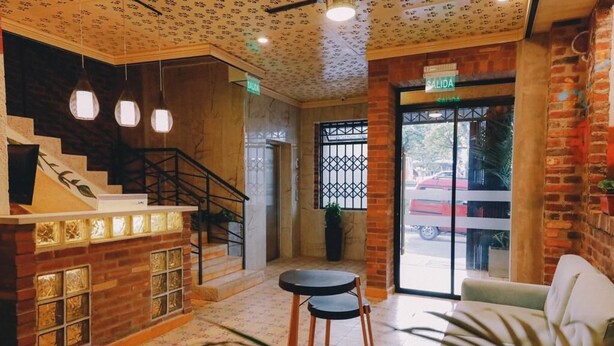 A lobby with a staircase, a reception desk, and a view of the outside.
