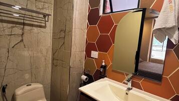 A bathroom with a toilet, sink, mirror, and towel rack.