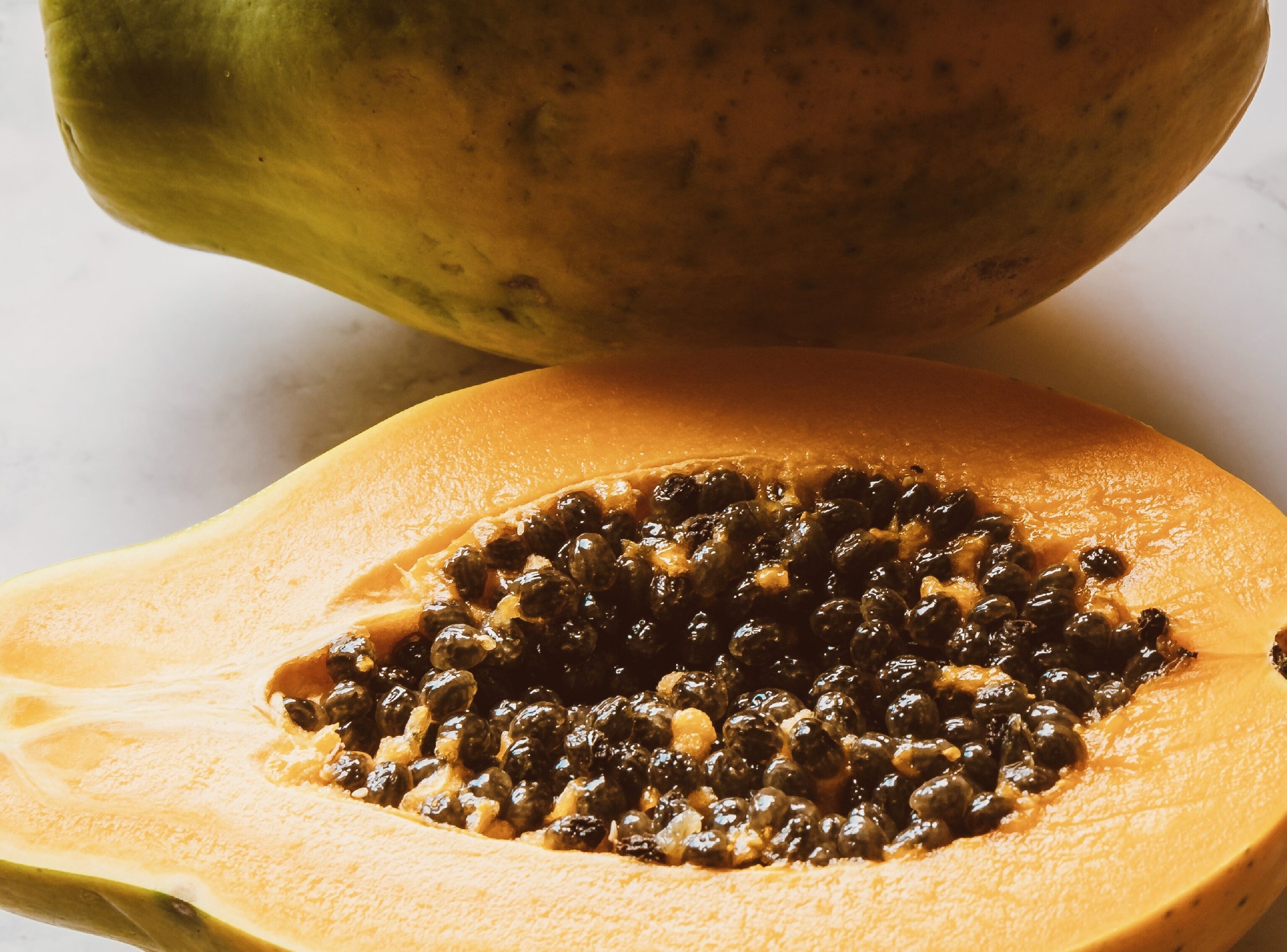 En papaya halveret, med frøene synlige.