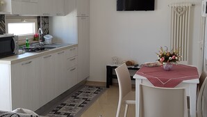 A compact kitchen with a microwave, sink, and cabinets. A dining area with a table and chairs is adjacent to the kitchen. - COZY AND ELEGANT COTTAGE WITH PENTHOUSE (Polignano a Mare)