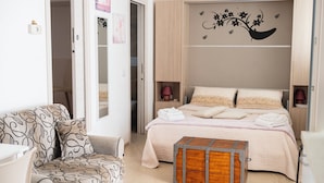 A bedroom with a bed, a chair, a bedside table, and a decorative wall. - COZY AND ELEGANT COTTAGE WITH PENTHOUSE (Polignano a Mare)