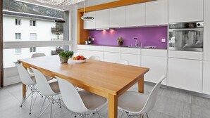 Eine moderne Küche mit weißen Schränken, einem Holztisch und einer lilafarbenen Akzentwand.