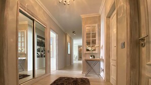A hallway with a dark brown rug, a glass door leading to a room, and a small table with a vase of flowers.