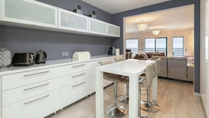 A modern kitchen with white cabinetry, a bar area, and a seating area with a view.