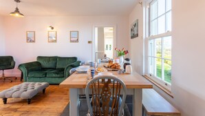 Ein gemütliches Wohnzimmer mit einem grünen Sofa, einem Holzesstisch, der mit Tellern, Tassen und einem Strauß Tulpen gedeckt ist.