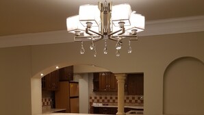 Un comedor con candelabro, una cocina al fondo y una mesa con sillas.
