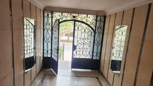 Un pasillo con piso de baldosas, una lámpara en el techo y una reja metálica decorativa al final.