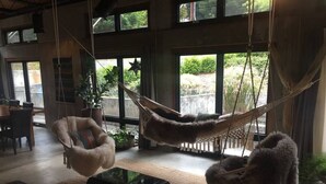 A spacious living area with a hammock chair, a cushioned chair, and a glass coffee table. - Concrete Loft in the Redwoods (Eureka)