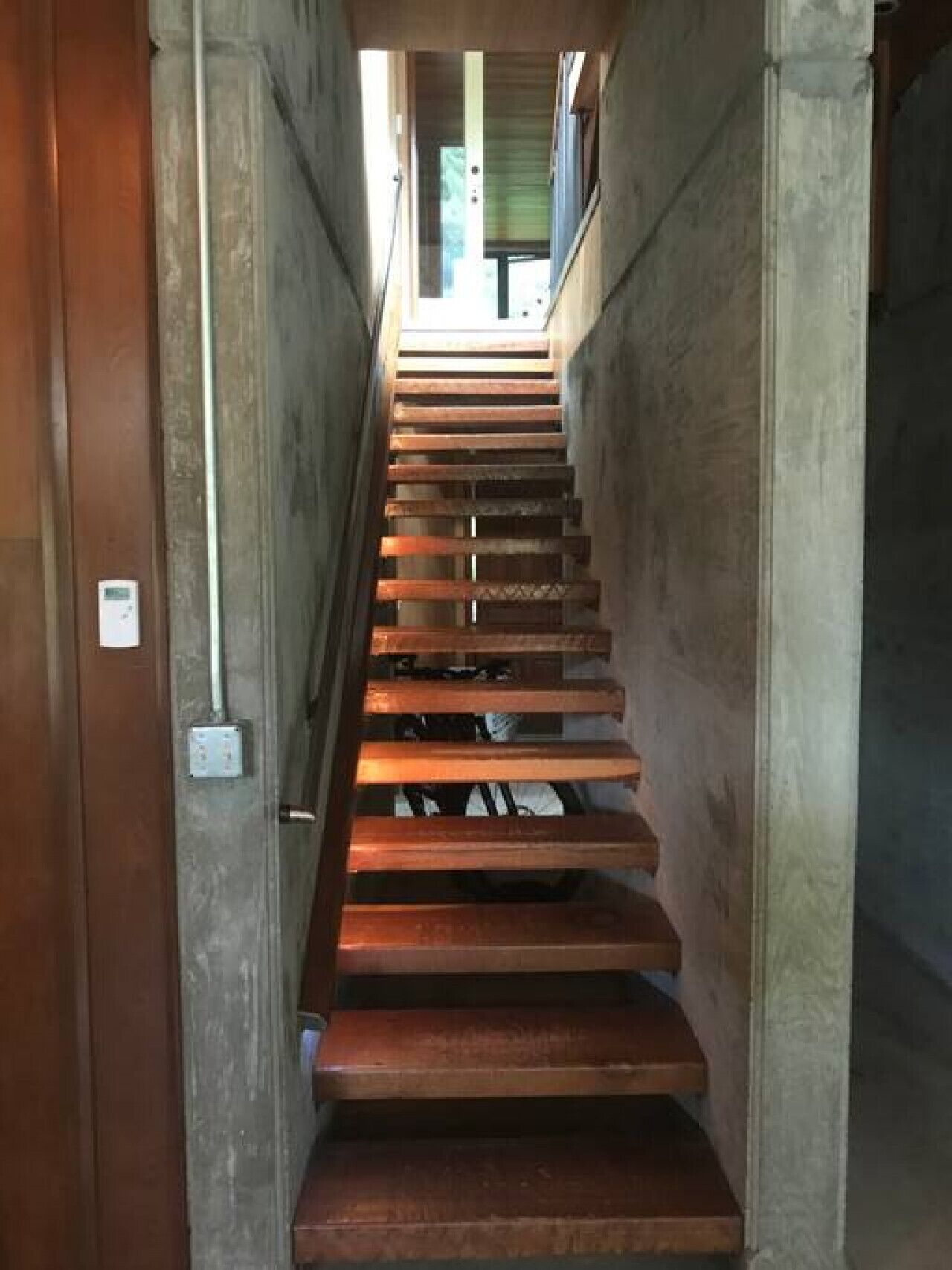 A wooden staircase with a handrail, leading to an upper floor.