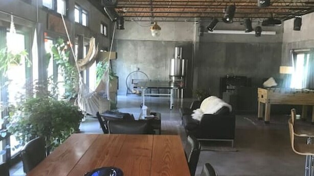 A spacious room with a wooden dining table, black leather chairs, and a hanging light fixture. - Concrete Loft in the Redwoods (Eureka)