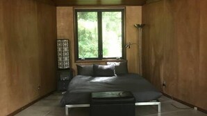 A bedroom with a bed, a window, a nightstand, and a rug. - Concrete Loft in the Redwoods (Eureka)