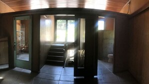 A modern interior with a staircase leading to a second floor, a visible bathroom, and a large window allowing natural light. - Concrete Loft in the Redwoods (Eureka)
