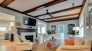 A spacious living room with a fireplace, two sofas, a coffee table, and a ceiling fan. - PREMIER Landmark Home Located in Old Town Bluffton  (Bluffton)