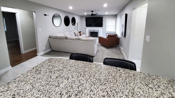 A spacious living room with a large sofa, a fireplace, and a dining area with a patterned tablecloth. - Location. Location. Location. Only 15 minute walk to Mackey Arena. (West Lafayette)