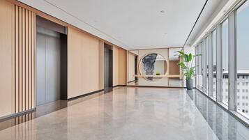 A modern hallway with a polished floor, wooden paneling, a circular marble feature, and a potted plant.