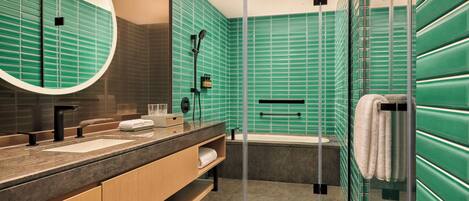 A modern bathroom with a glass-enclosed shower, a large mirror, and a vanity with a sink and towel rack.