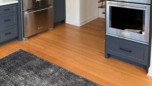Una cocina moderna con refrigerador de acero inoxidable, horno doble y armarios oscuros.