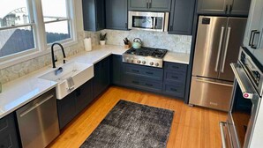 Una cocina moderna con armarios oscuros, electrodomésticos de acero inoxidable, microondas, estufa y lavavajillas.