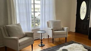 Una sala de estar con dos sillones, una mesita redonda y una alfombra de piel blanca.