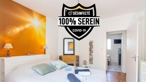 A hotel room with a bed, pillows, a nightstand, a lamp, a framed picture, and a fireplace. - L'Aparté ★ HYPER CENTRE ★ LUMINEUX ★ (Lorient)