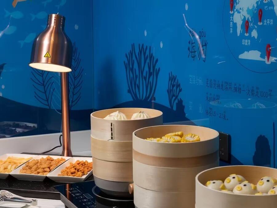 A dining area with a table set for a meal, including a lamp, a map, and food containers.