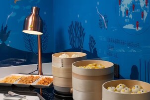 Un coin repas avec une table mise pour le repas, comprenant une lampe, une carte et des récipients contenant de la nourriture.