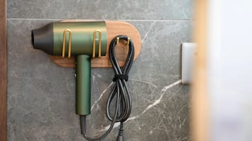 Un sèche-cheveux fixé sur une planche de bois, avec un cordon enroulé.
