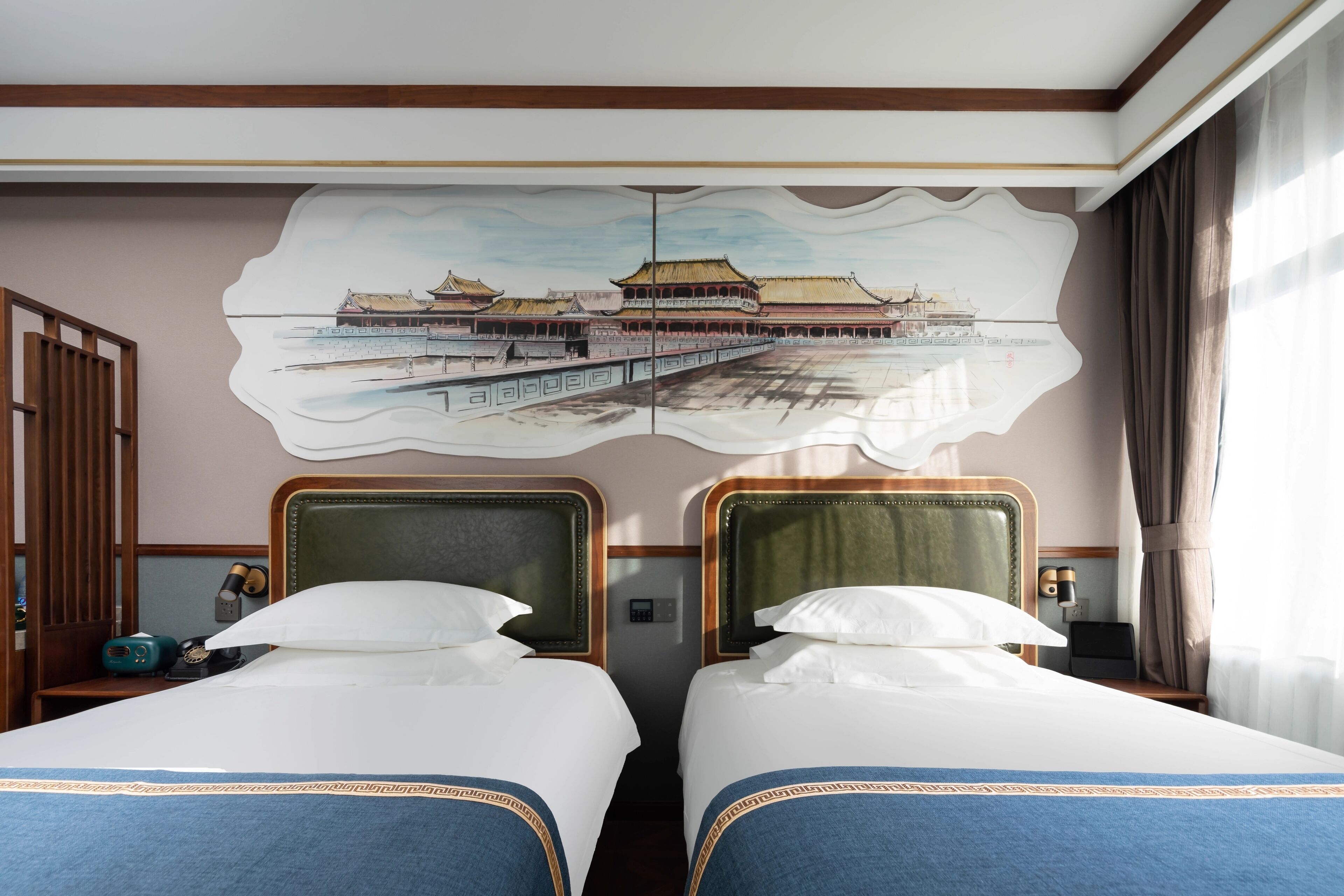 A hotel room with two beds, a large mural of a traditional building, and a window with curtains.