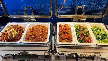 A buffet with labeled food containers including fried pancakes, soy sauce fried rice, braised meatballs, and various vegetables.