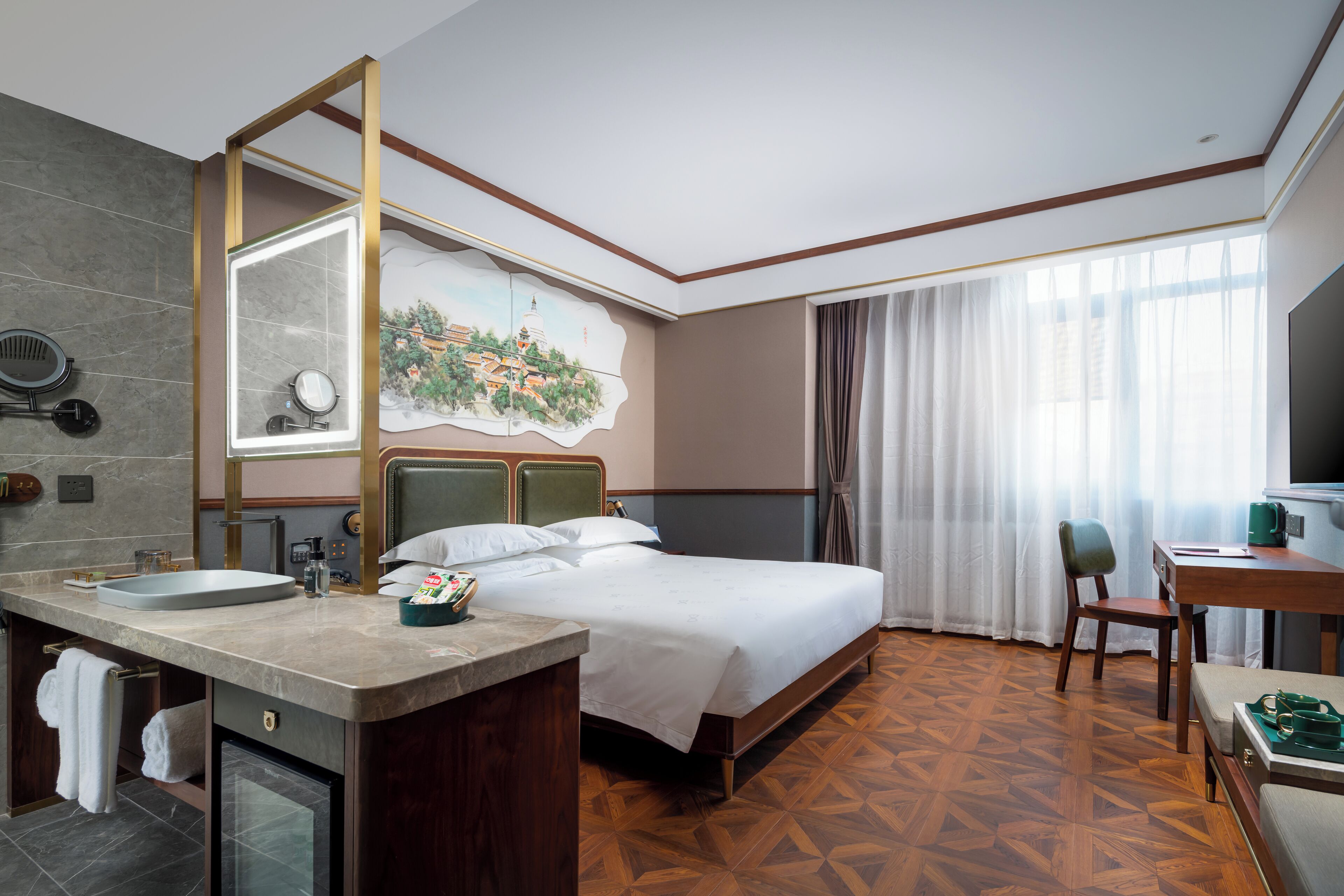 Quarto de hotel com uma cama grande, uma escrivaninha de madeira, banheiro com pia e espelho, e um quadro na parede.
