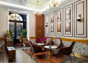 A lobby with a wooden reception desk, leather chairs, a round table, and framed artwork on the walls. - Nostalgia S Hotel (Beijing Xidan Financial Street Branch) (Beijing)
