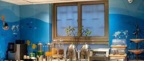 Una barra de desayuno con máquinas de café, dispensadores de alimentos y un ventanal decorativo.