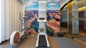 Ein modernes Fitnessstudio mit Laufband, Crosstrainer und Kurzhanteln.