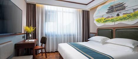 A hotel room with a large bed, a desk with a chair, a TV, and a painting of a traditional building on the wall.