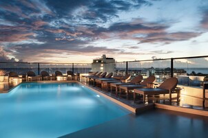 Zona de piscina en la azotea con sillones y vistas al horizonte de la ciudad.