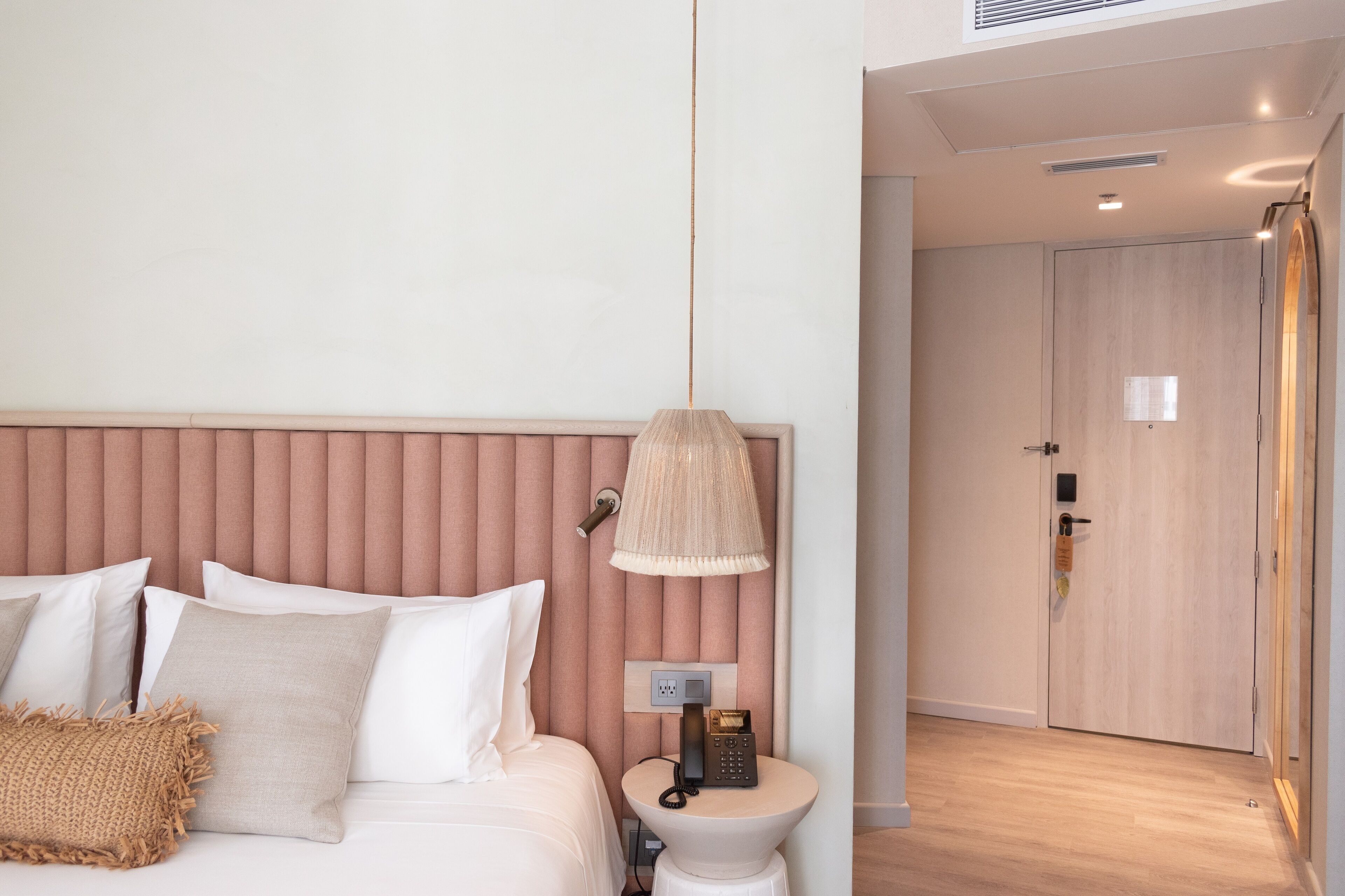 A hotel room with a bed, bedside lamp, and a phone on a small table.