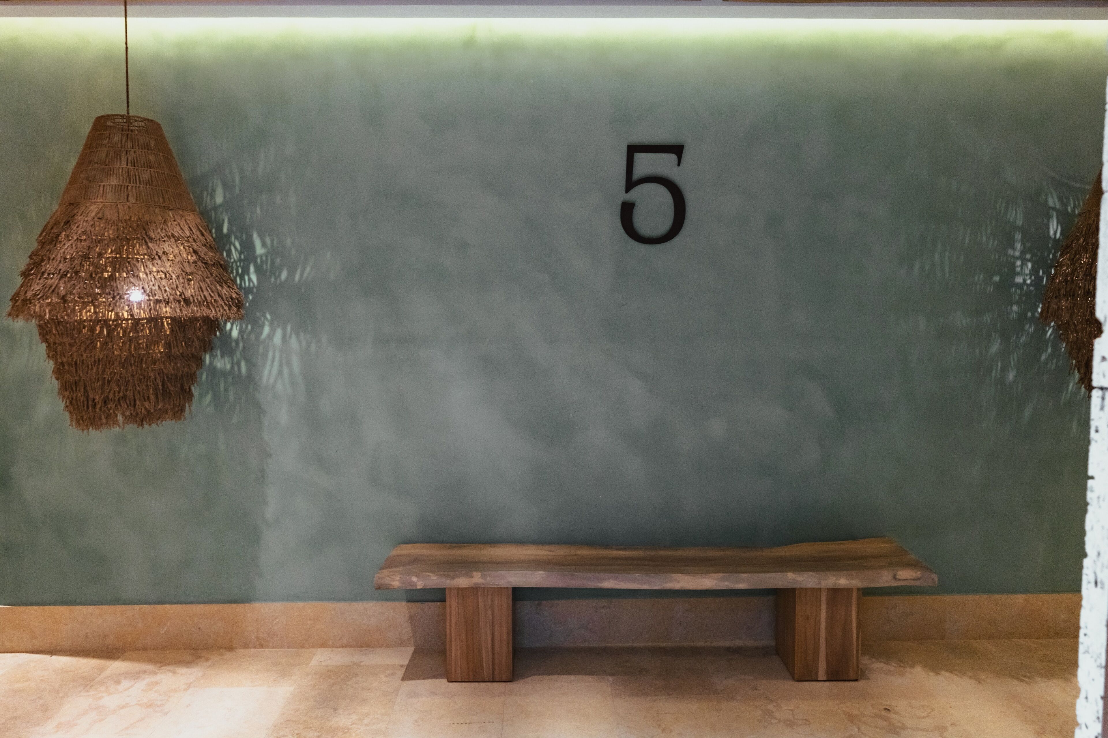 A wooden bench against a green wall with the number 5.