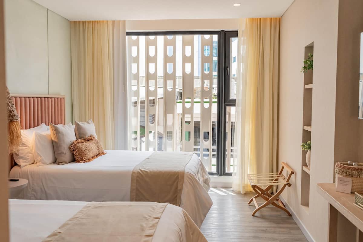 Ein Hotelzimmer mit zwei Betten, einem Balkon und Blick sowie einem Holzbett.