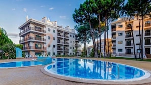 A modern apartment building with a swimming pool and outdoor seating area.