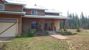 A two-story house with a covered porch, a garage, and a stone pathway leading to the entrance. - ATV/Snowmobiler's Paradise - Ride Out from the Cabin for Miles on End! (Placerville)