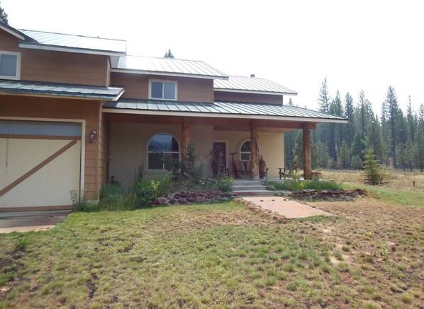 A two-story house with a covered porch, a garage, and a stone pathway leading to the entrance.